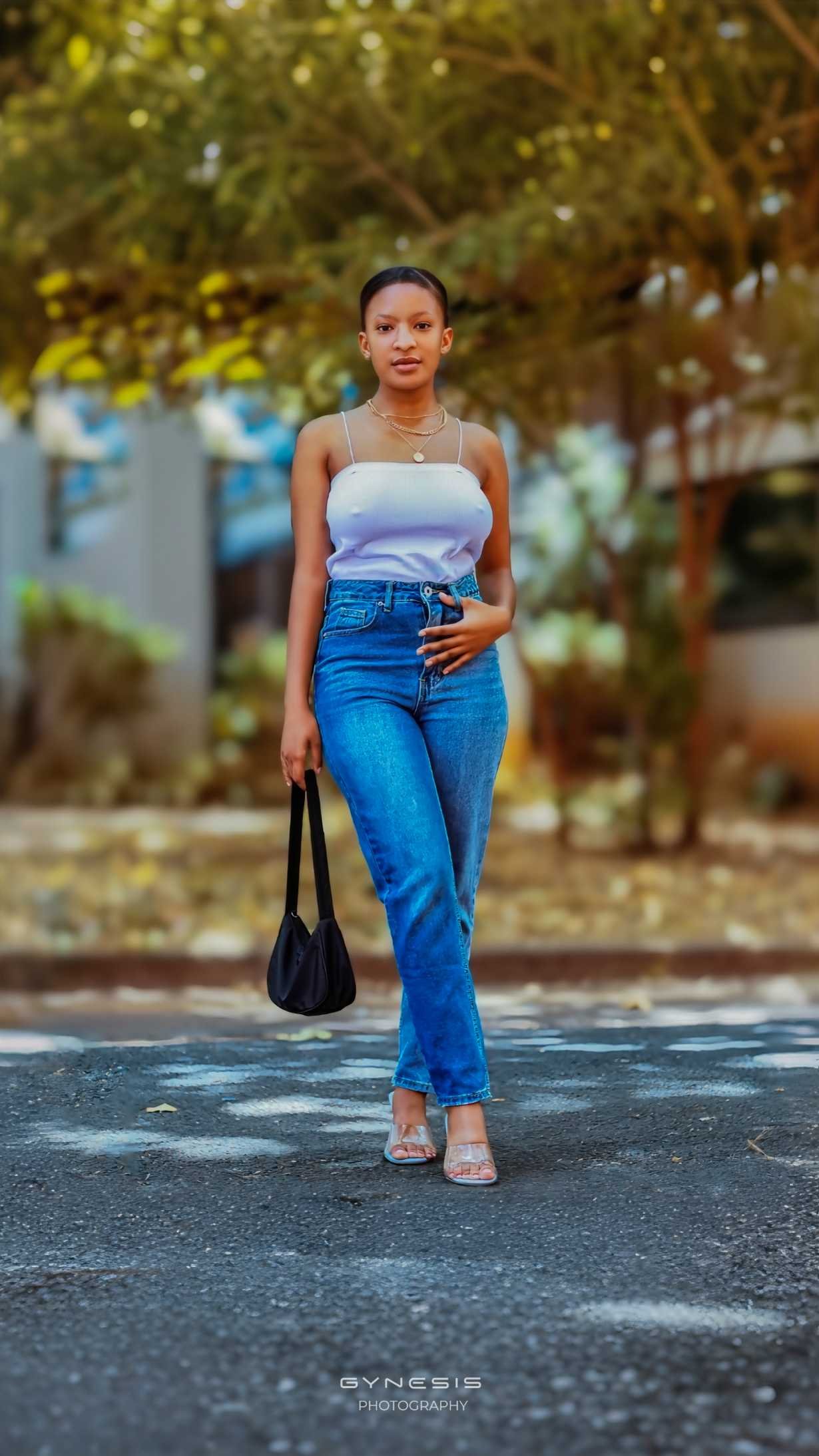 Lifestyle birthday photoshoot in Pretoria, Pretoria West, Pretoria North, Gauteng, South Africa featuring a model in denim jeans and a white top, posing confidently on the street.