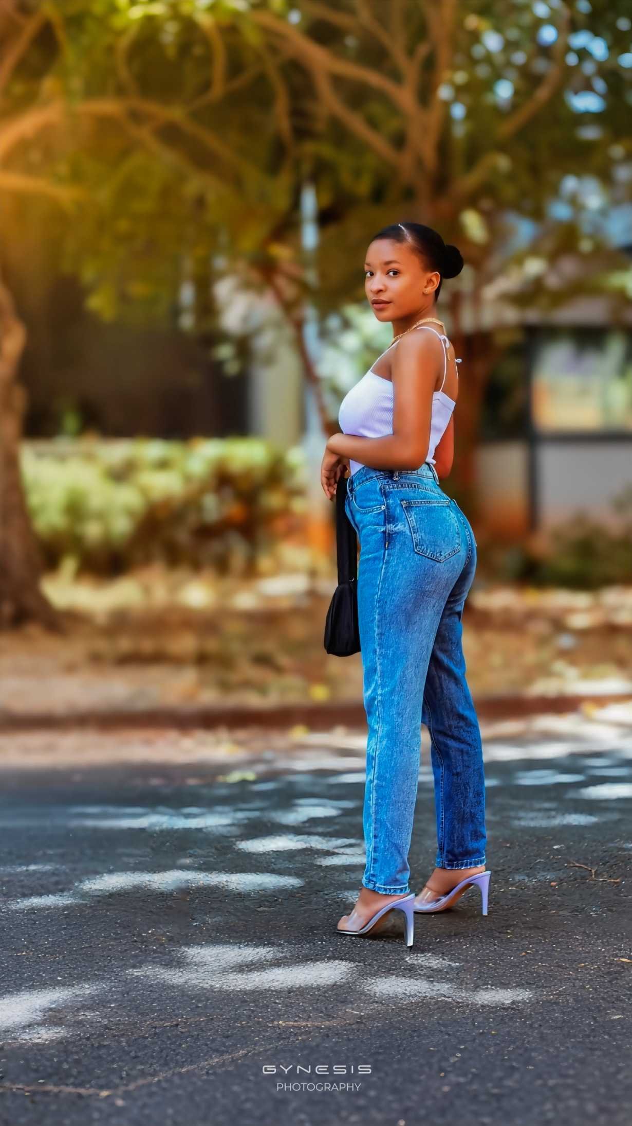 Lifestyle birthday photoshoot in Pretoria, Pretoria West, Pretoria North, Gauteng, South Africa featuring a model in a stylish outfit of denim jeans and a white top, posing outdoors.